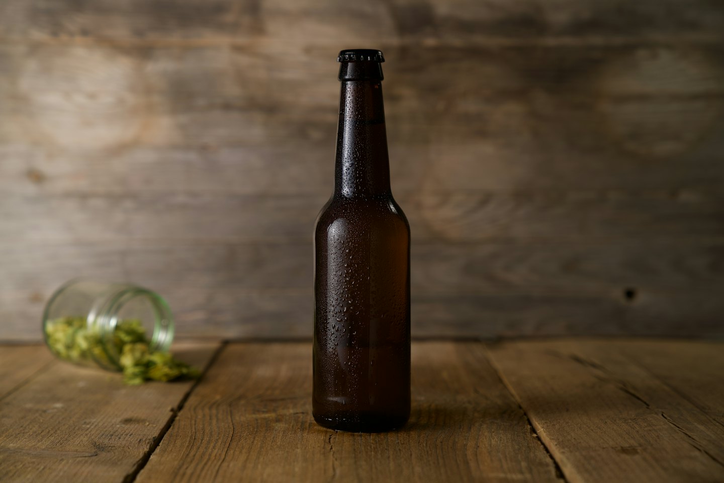 Una bottiglia di birra ambrata con condensa su un tavolo di legno.