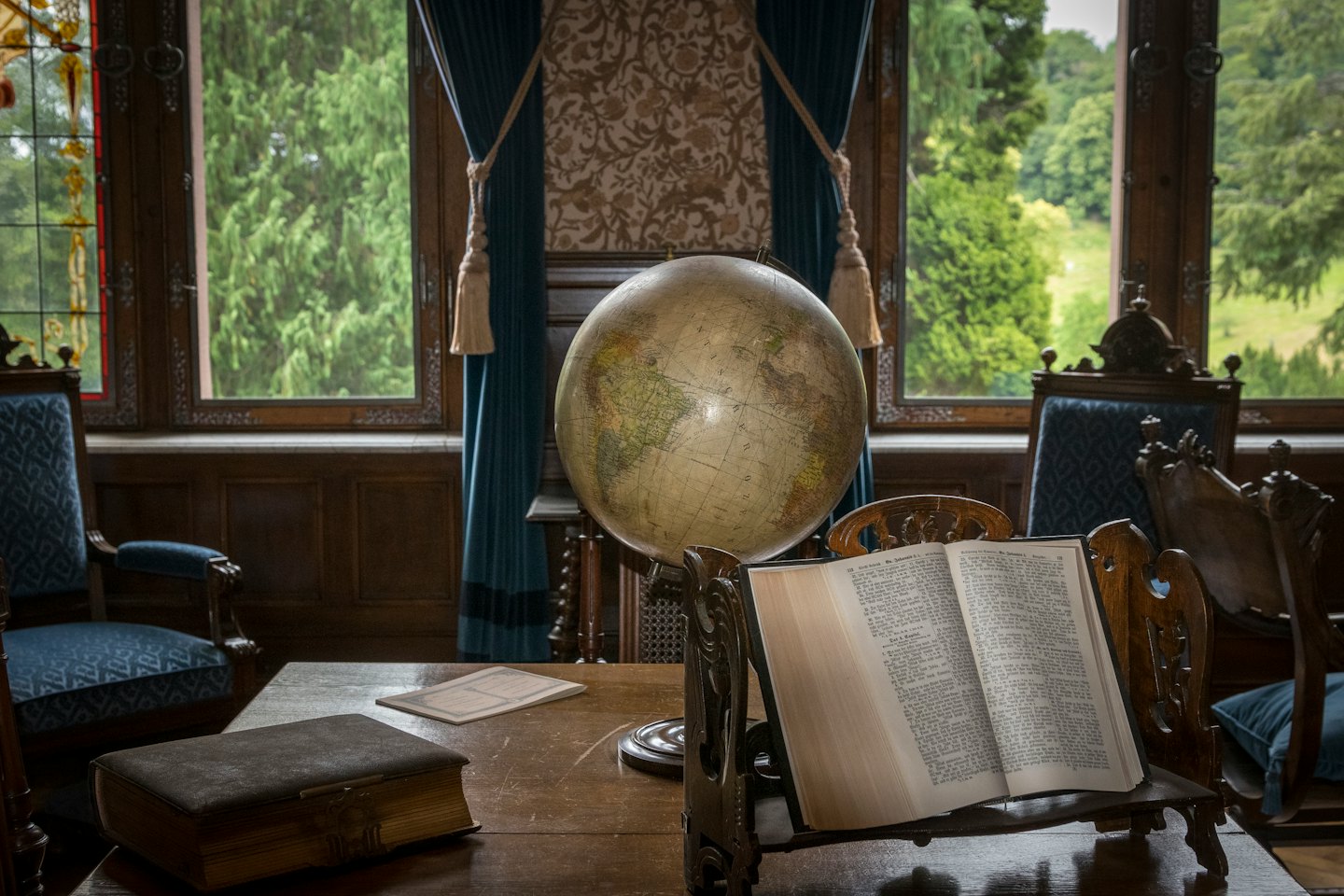 Scrivania in legno intarsiato con mappamondo e libri in uno studio.